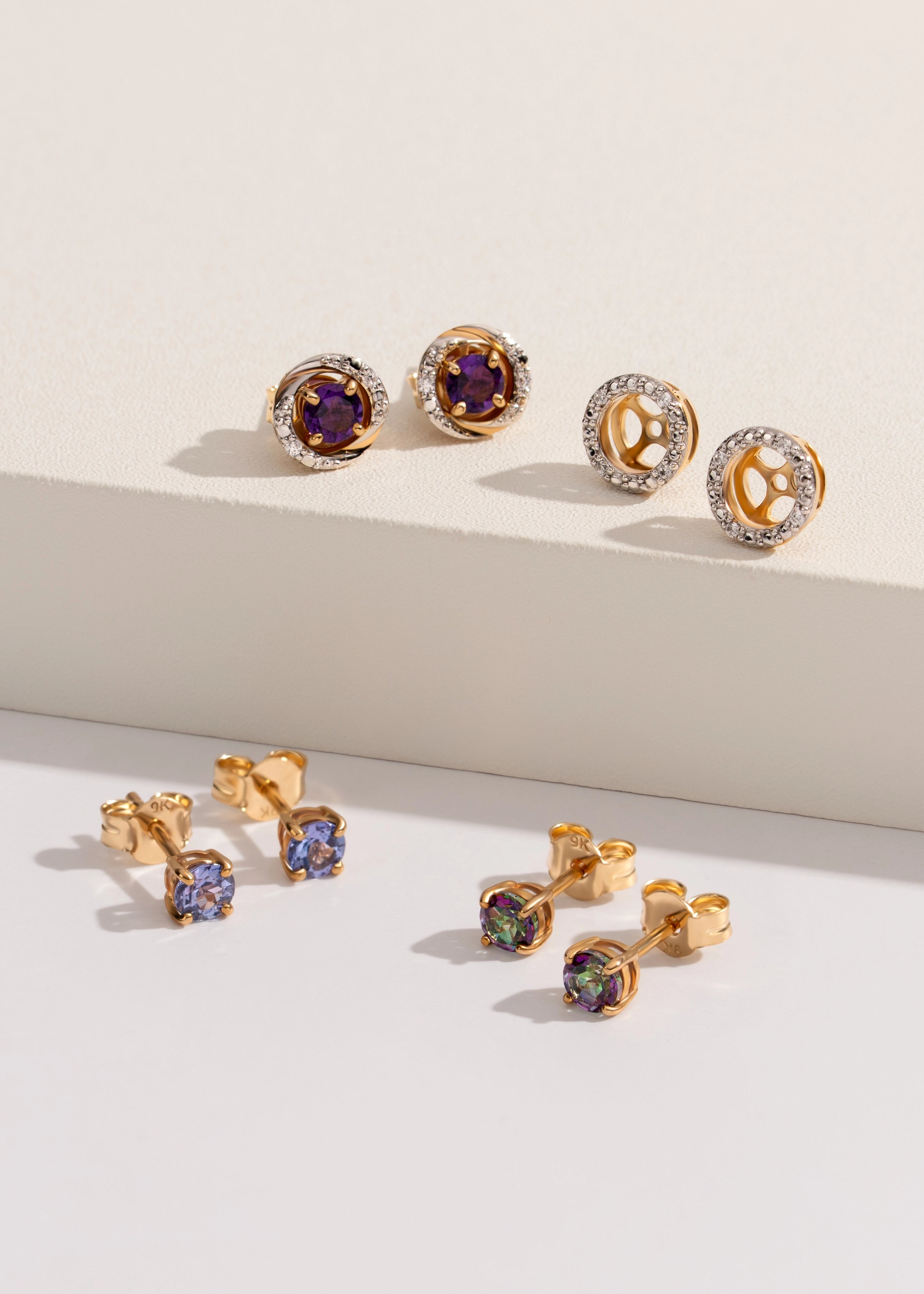 Gold earrings with gemstones on a light background